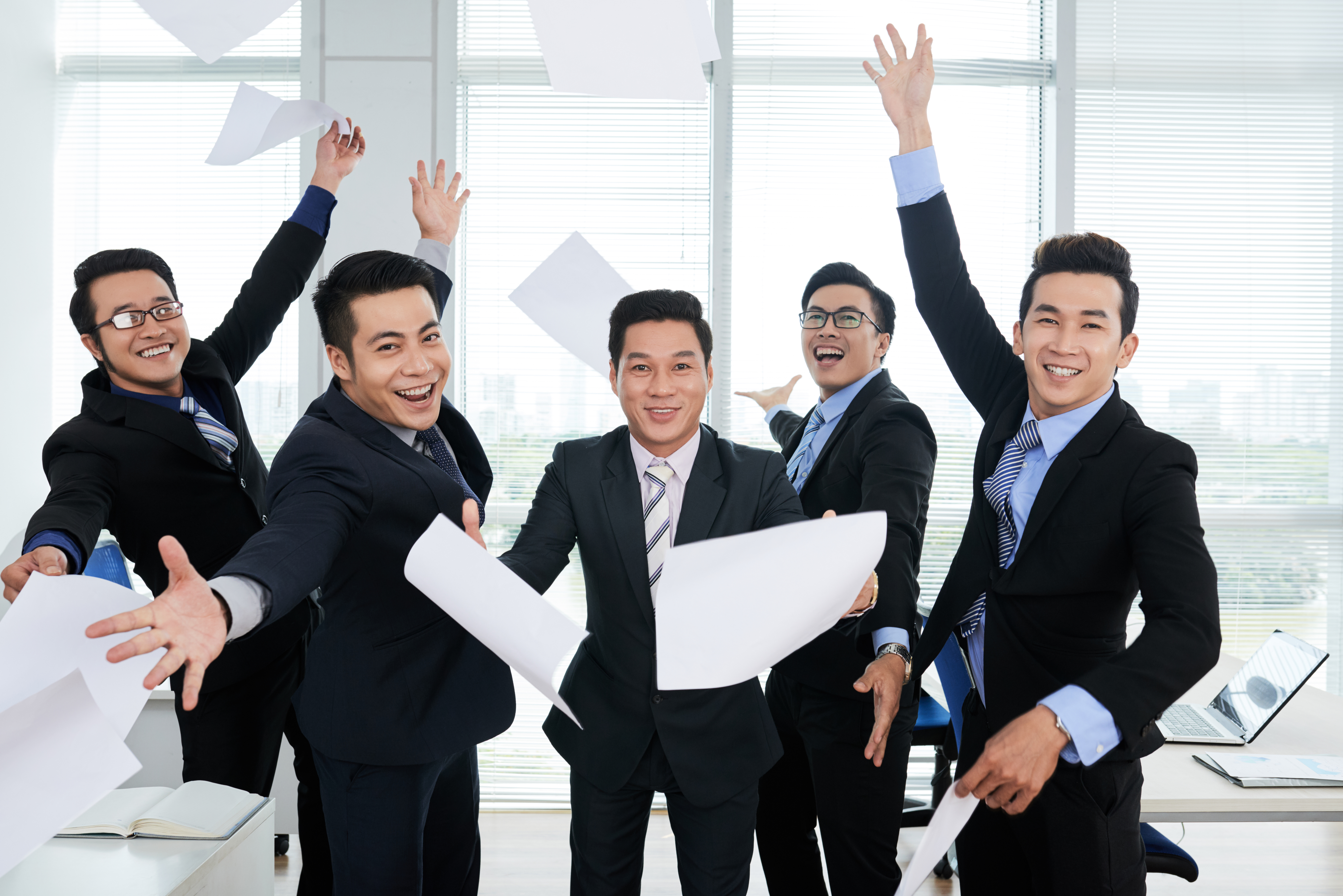 group-cheerful-asian-businessmen-suits-throwing-documents-up-air-office